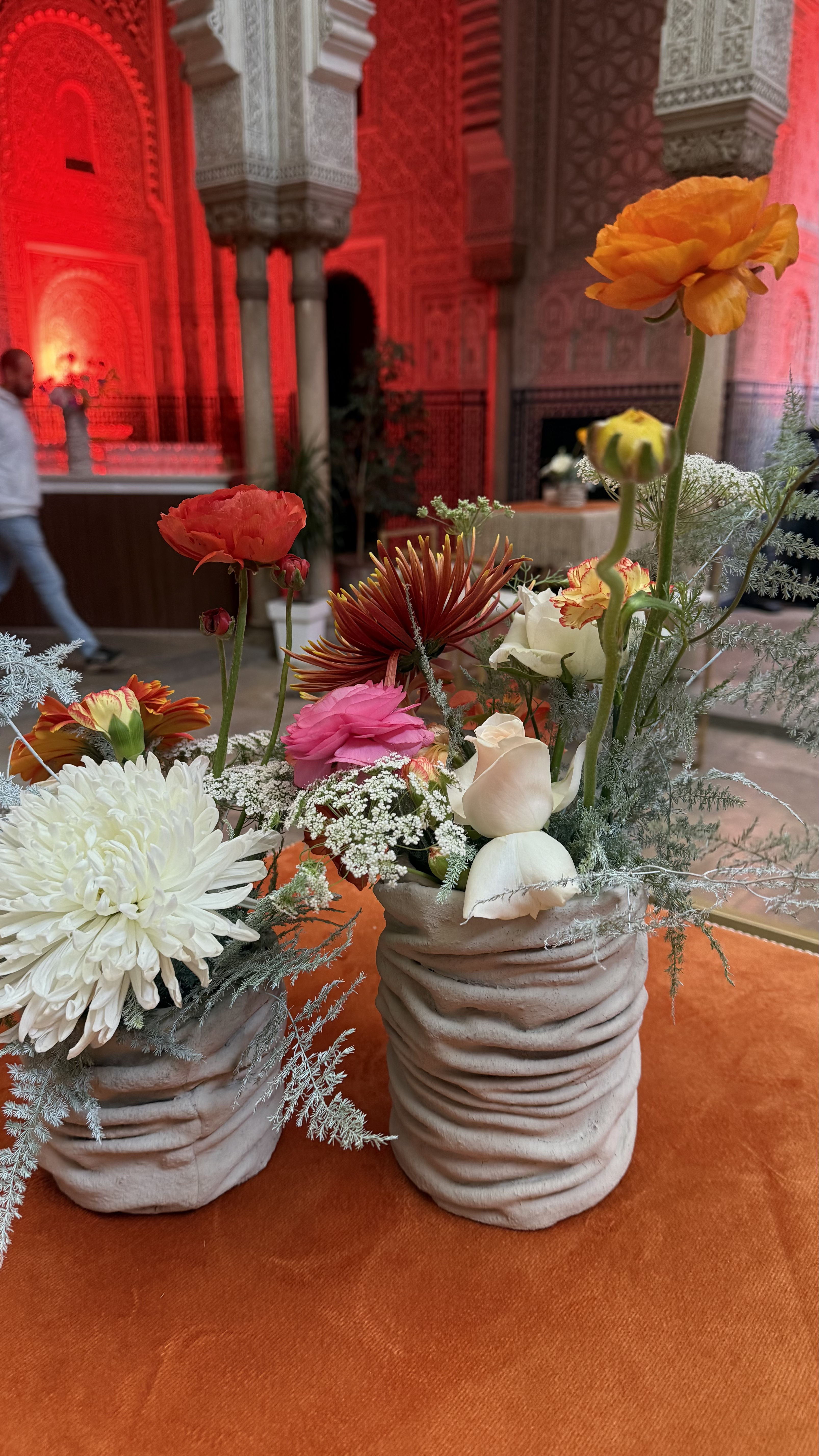 Corporate event for Orange at the Mahkama du Pacha in Habous, Casablanca — orange linens, terracotta vases with ranunculus and gerbera, candlelight and carved Moorish arches, produced by SBAI Events Production