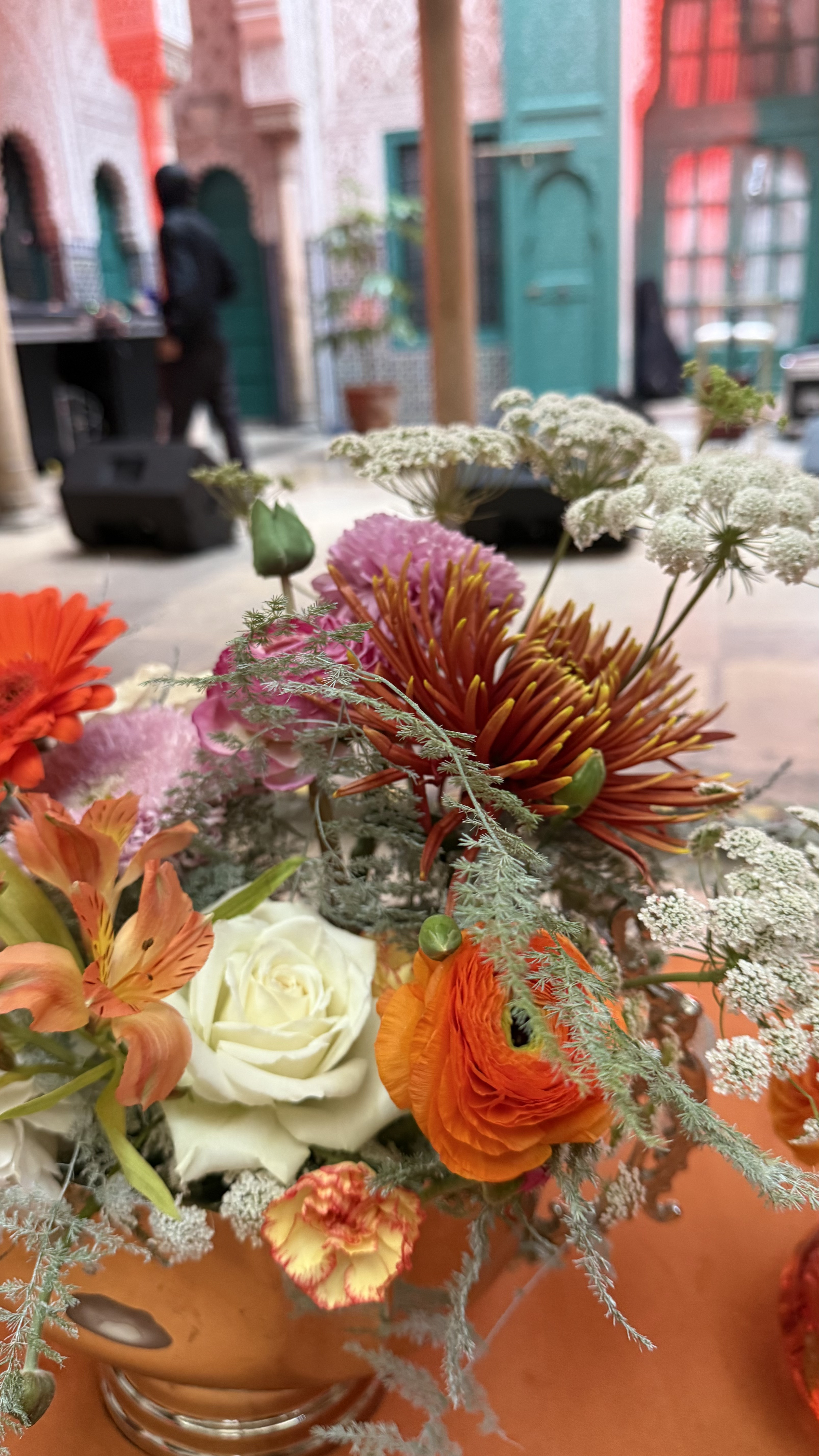 Corporate event for Orange at the Mahkama du Pacha in Habous, Casablanca — orange linens, terracotta vases with ranunculus and gerbera, candlelight and carved Moorish arches, produced by SBAI Events Production