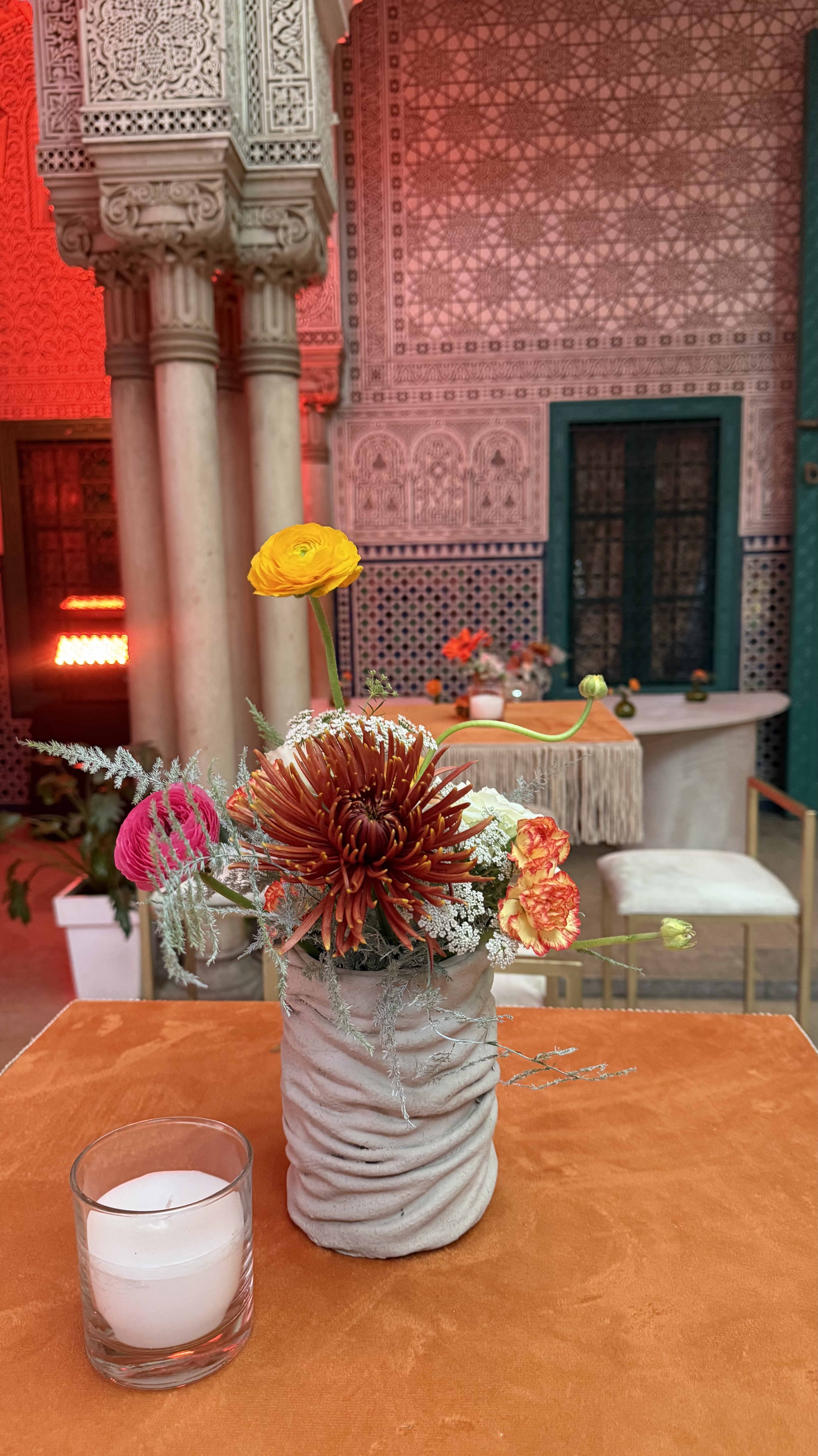 Corporate event for Orange at the Mahkama du Pacha in Habous, Casablanca — orange linens, terracotta vases with ranunculus and gerbera, candlelight and carved Moorish arches, produced by SBAI Events Production