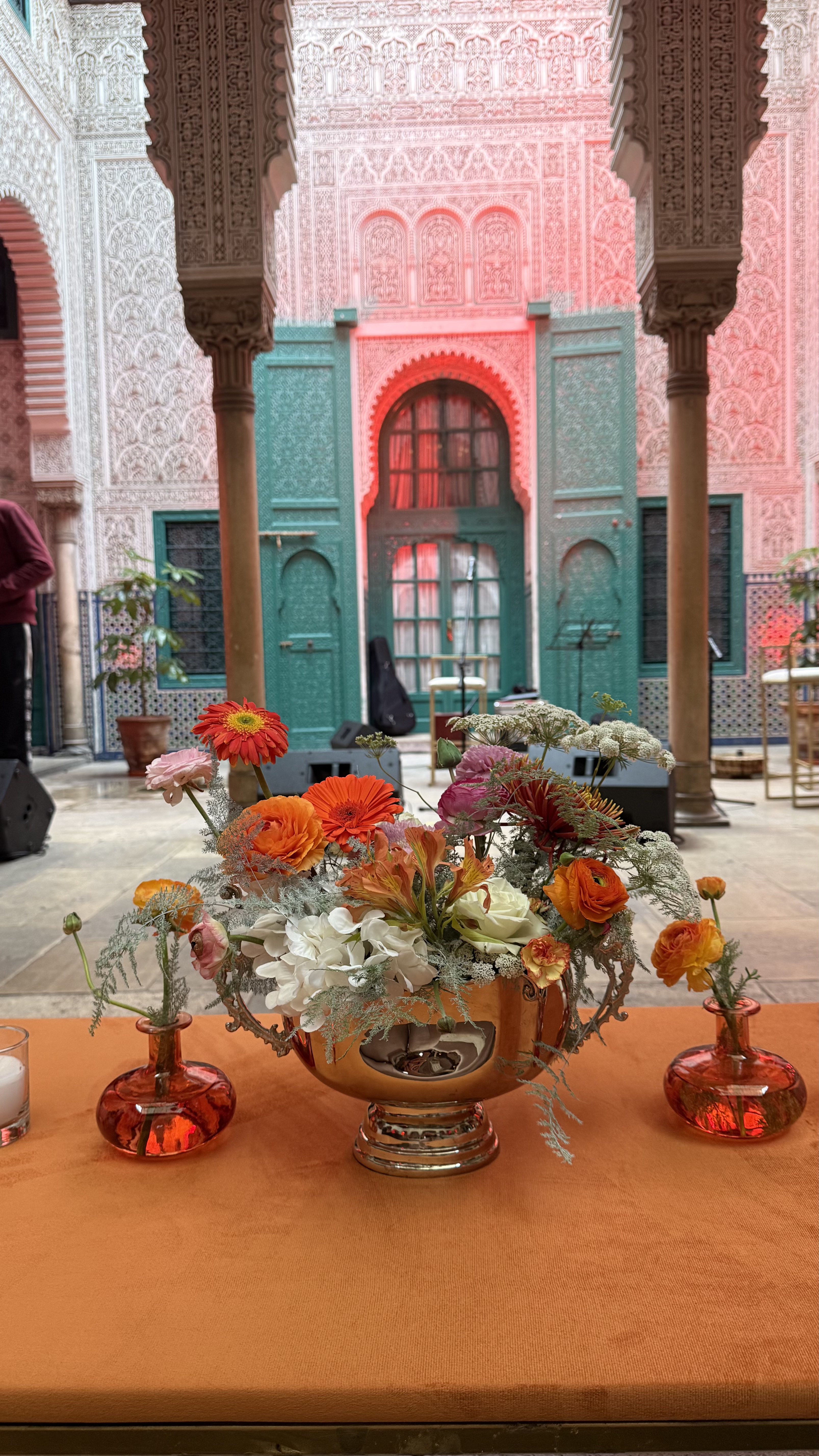 Corporate event for Orange at the Mahkama du Pacha in Habous, Casablanca — orange linens, terracotta vases with ranunculus and gerbera, candlelight and carved Moorish arches, produced by SBAI Events Production