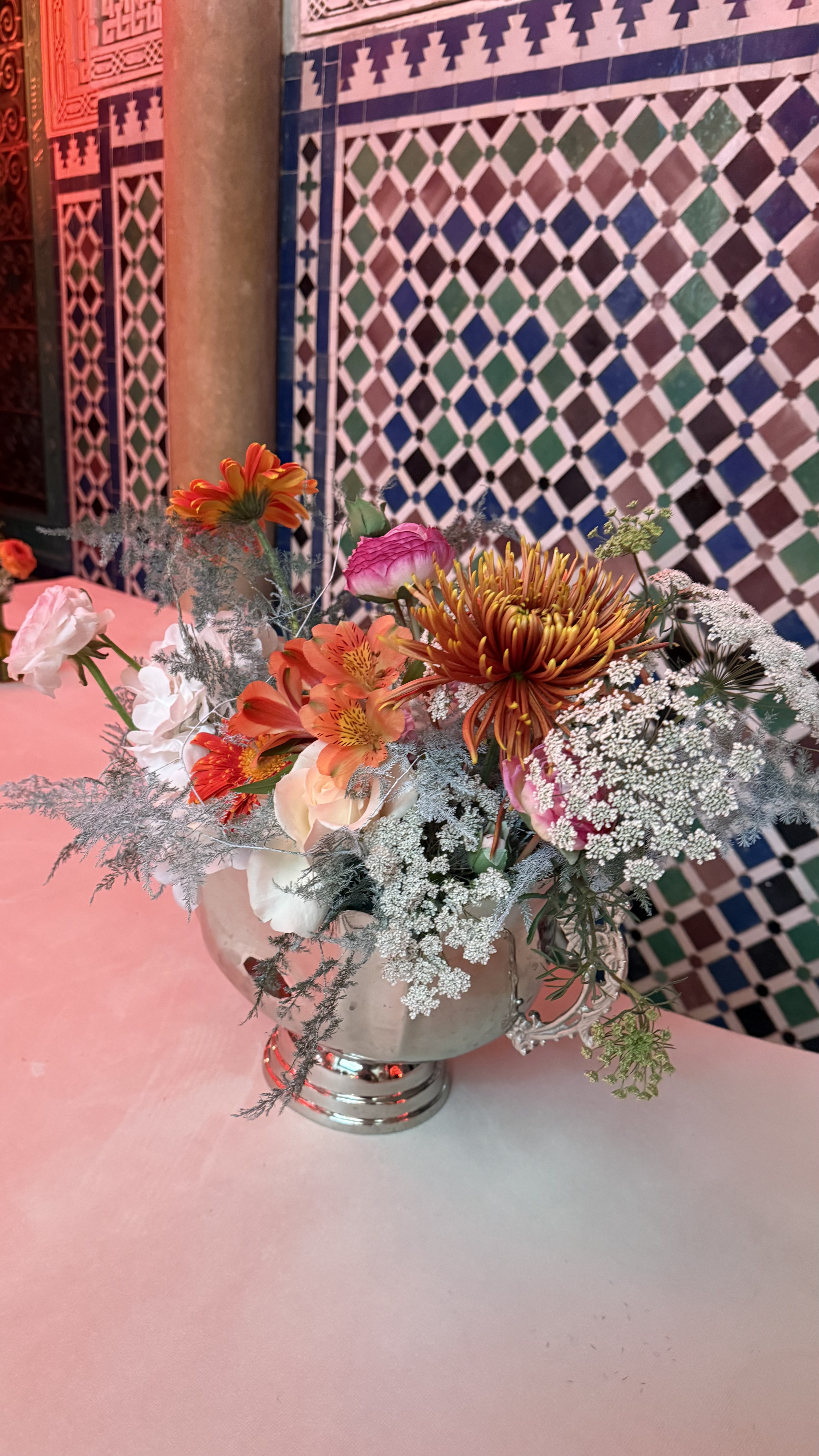Corporate event for Orange at the Mahkama du Pacha in Habous, Casablanca — orange linens, terracotta vases with ranunculus and gerbera, candlelight and carved Moorish arches, produced by SBAI Events Production