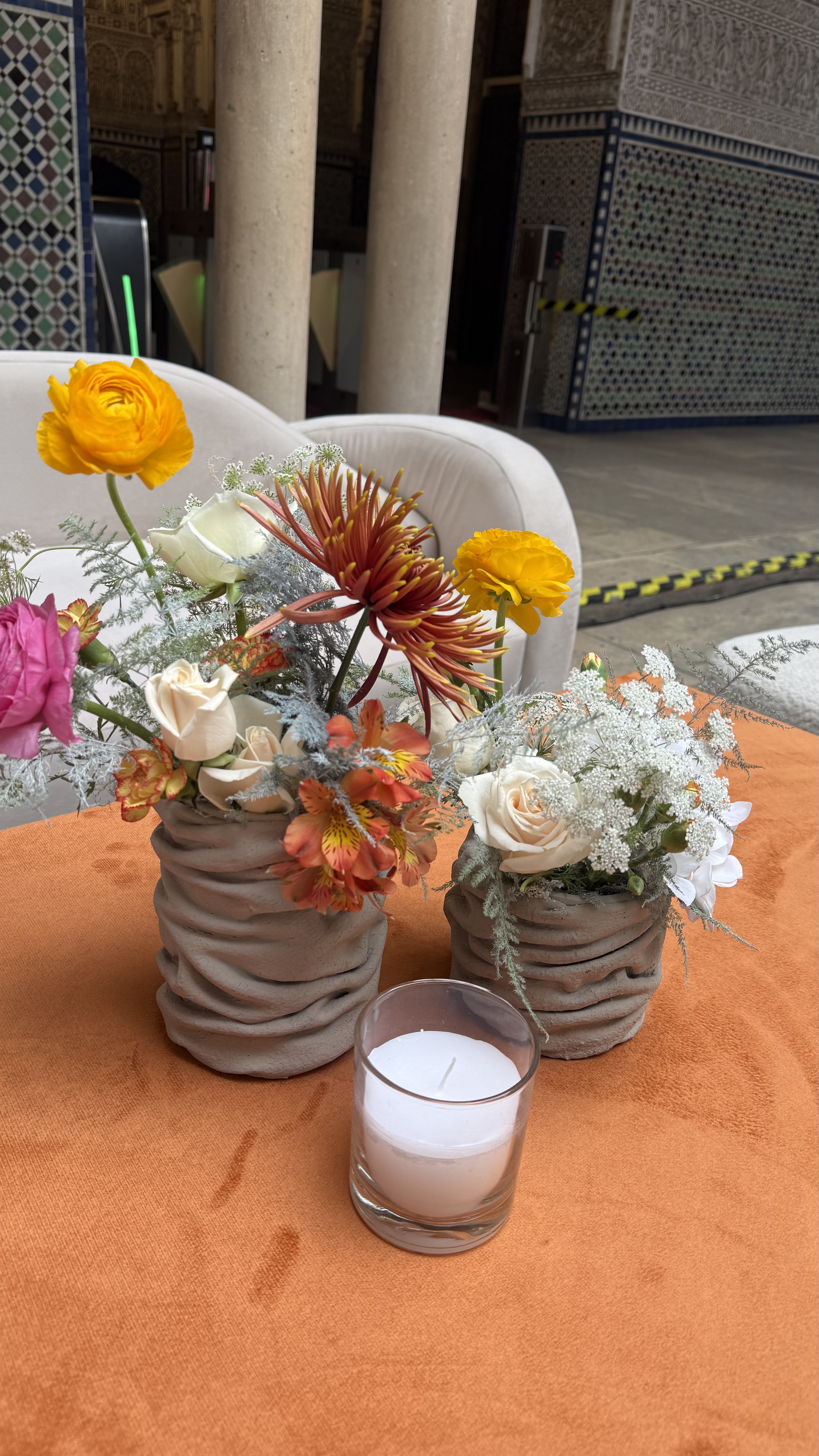 Corporate event for Orange at the Mahkama du Pacha in Habous, Casablanca — orange linens, terracotta vases with ranunculus and gerbera, candlelight and carved Moorish arches, produced by SBAI Events Production