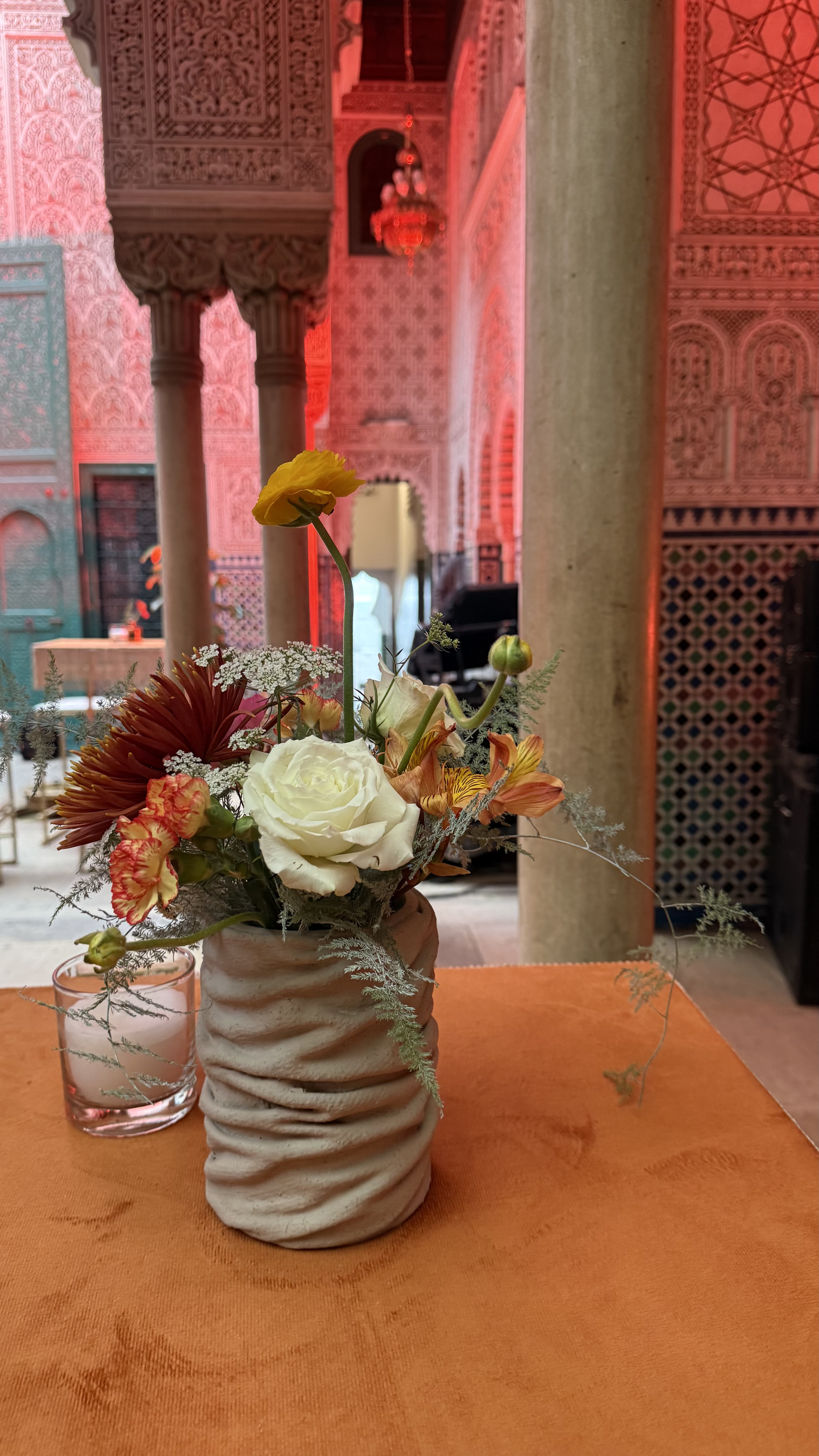 Corporate event for Orange at the Mahkama du Pacha in Habous, Casablanca — orange linens, terracotta vases with ranunculus and gerbera, candlelight and carved Moorish arches, produced by SBAI Events Production